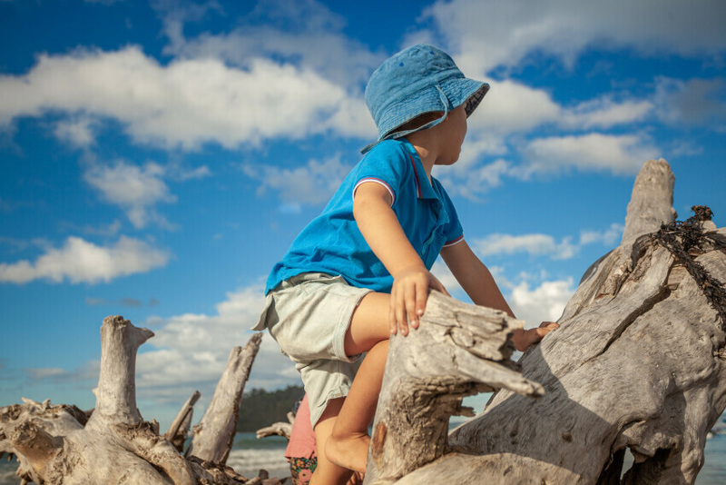 Two children playing in water wearing sunhats